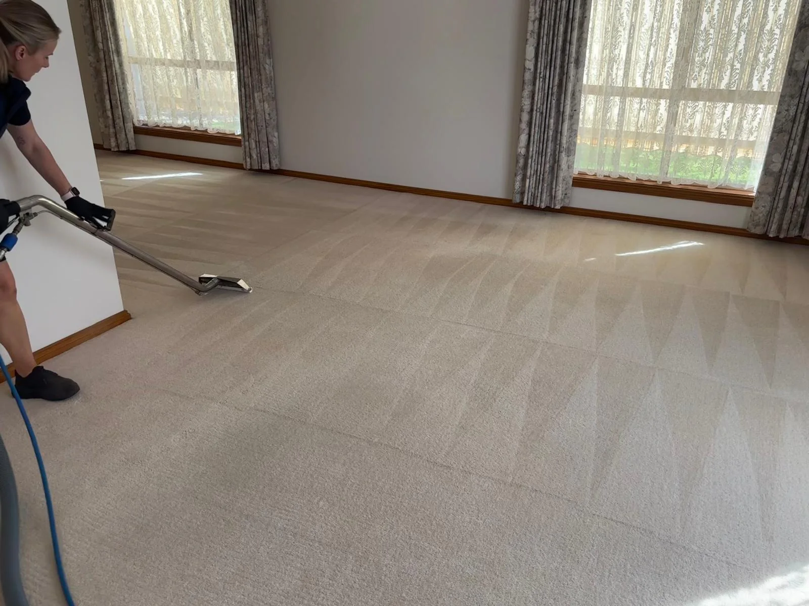 Carpet cleaner using an extraction wand on a bedroom carpet